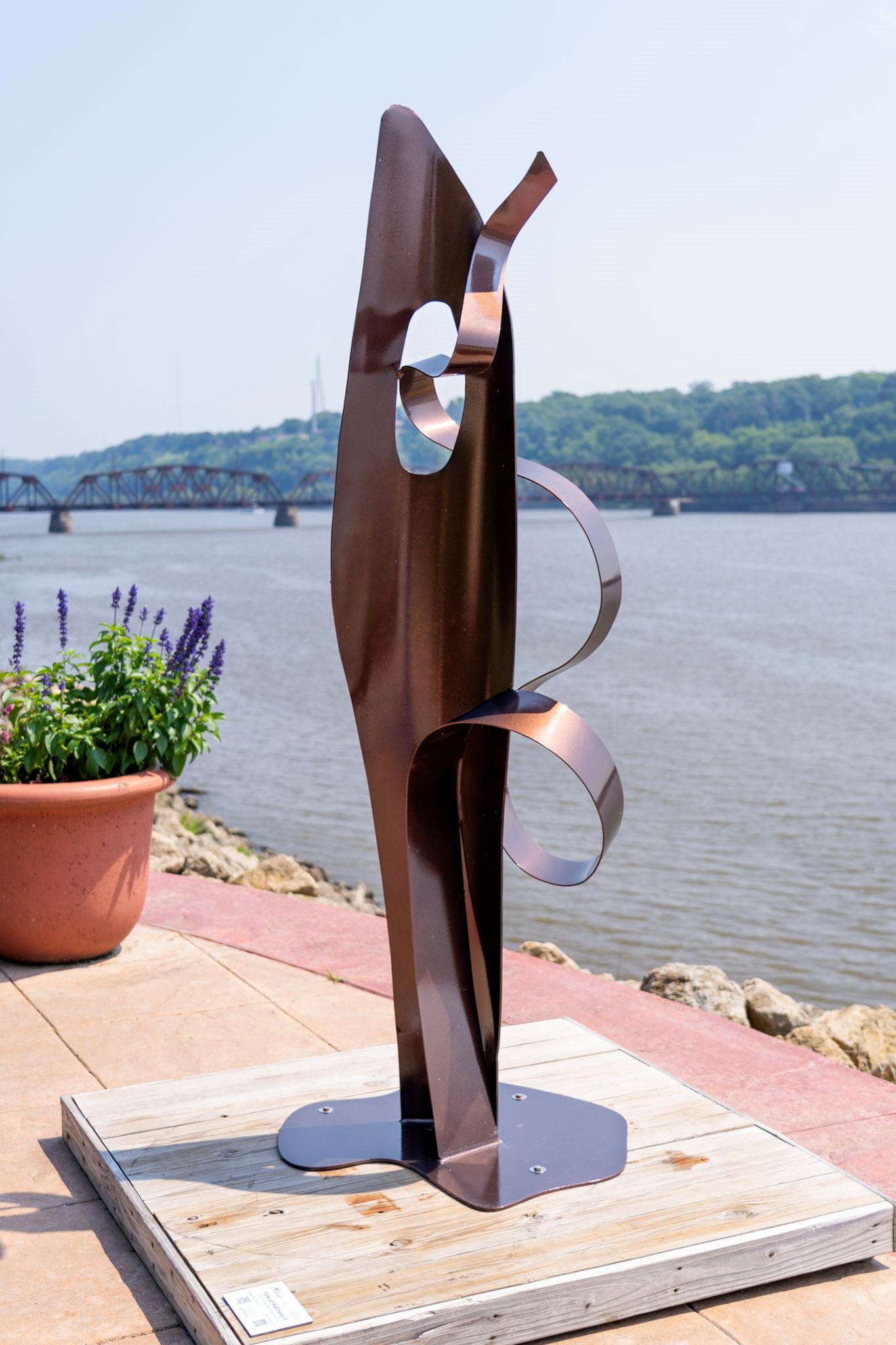 sculpture featuring a base and a flowing ribbon weaving through it's opening